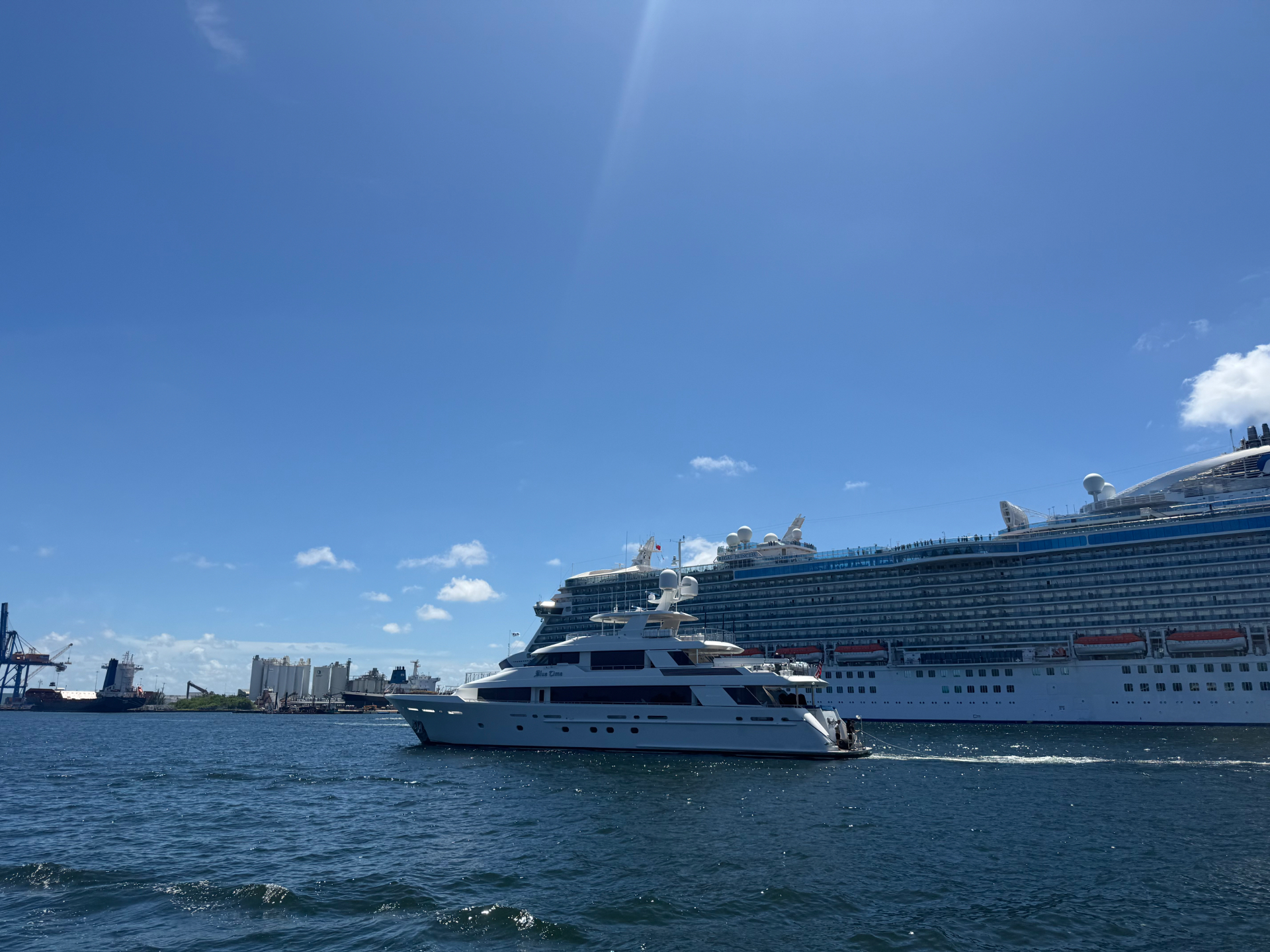 Motor yacht cruising past a docked cruise ship and cargo terminals at Port Everglades in Fort Lauderdale